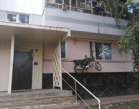 Пенсионер хранит мотоцикл под балконом